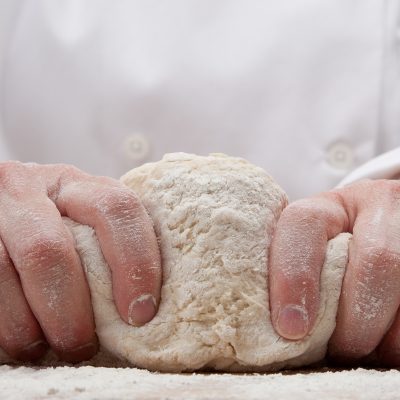 mãos amassando massa de pão, misturando os ingredientes